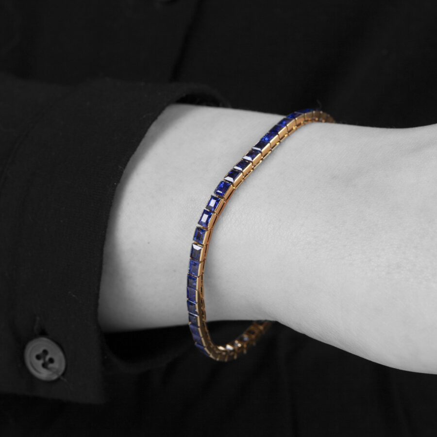 Een achttien karaat rosé gouden rivière armband bezet met baguette geslepen blauwe saffieren. Vervaardigd door Cartier in Parijs in 1918 en genummerd.