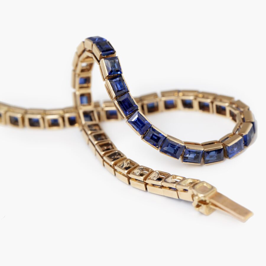 Een achttien karaat rosé gouden rivière armband bezet met baguette geslepen blauwe saffieren. Vervaardigd door Cartier in Parijs in 1918 en genummerd.