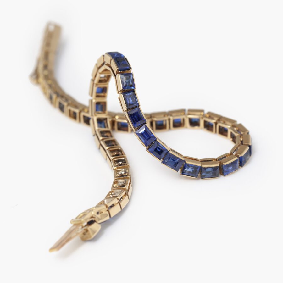 Een achttien karaat rosé gouden rivière armband bezet met baguette geslepen blauwe saffieren. Vervaardigd door Cartier in Parijs in 1918 en genummerd.